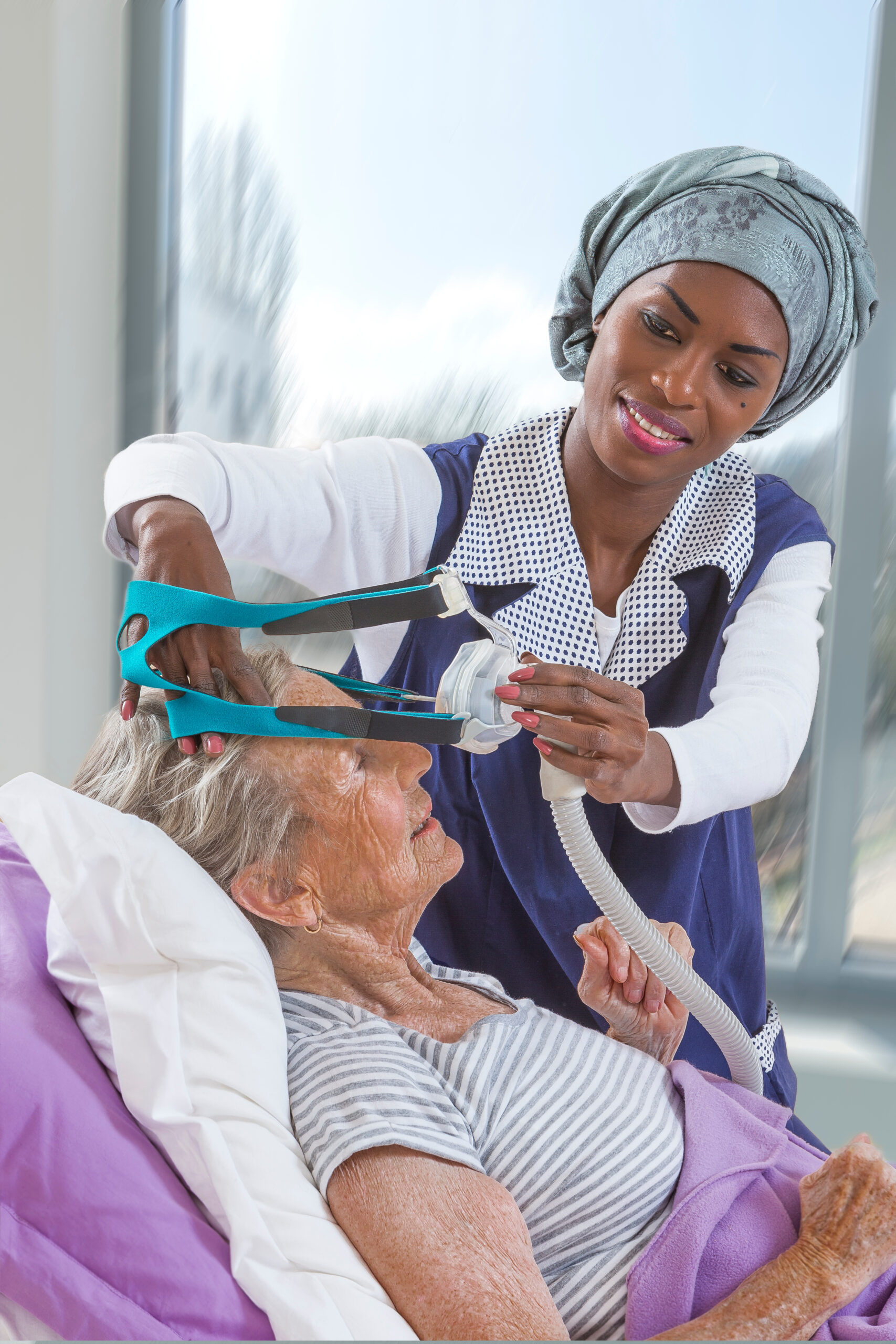 care giver Adjusting CPAP machine to an elderly woman at home care giver Adjusting CPAP machine to an elderly woman