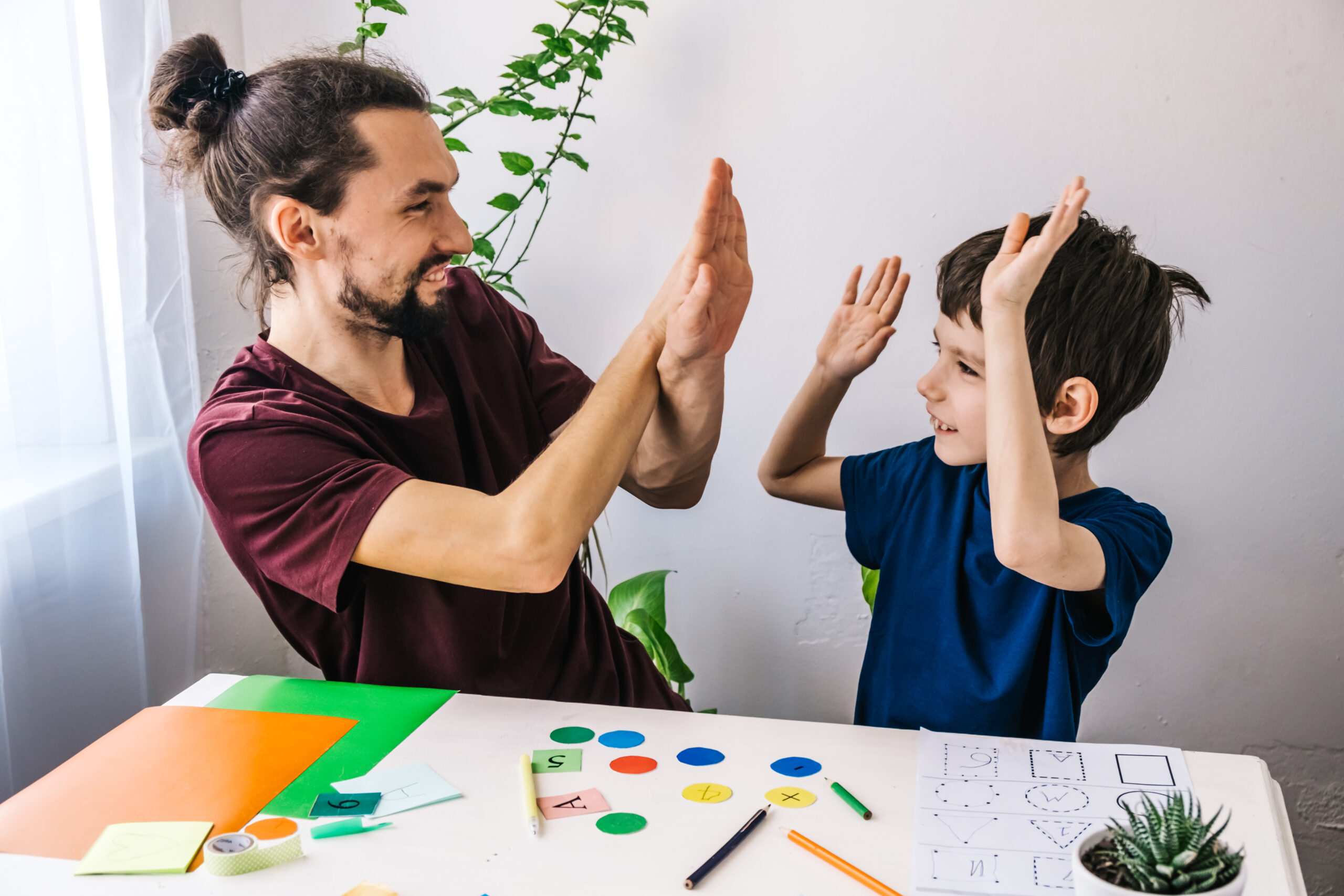 Happy autism boy during therapy with school tutor, learning and having fun together Happy autism boy during therapy with school tutor, learning and having fun together