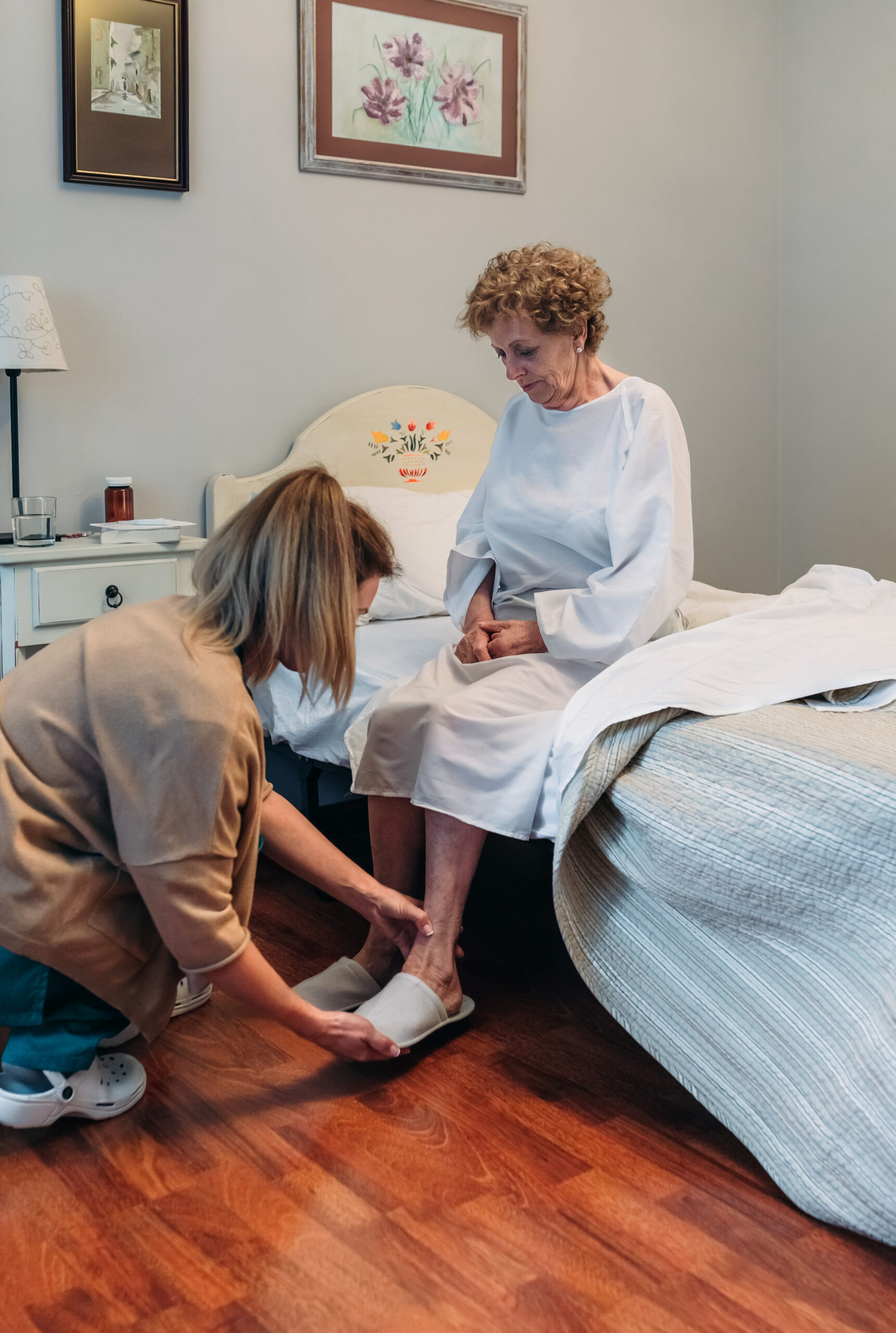 Carer wearing slippers to elderly patient Female carer wearing slippers to elderly female patient