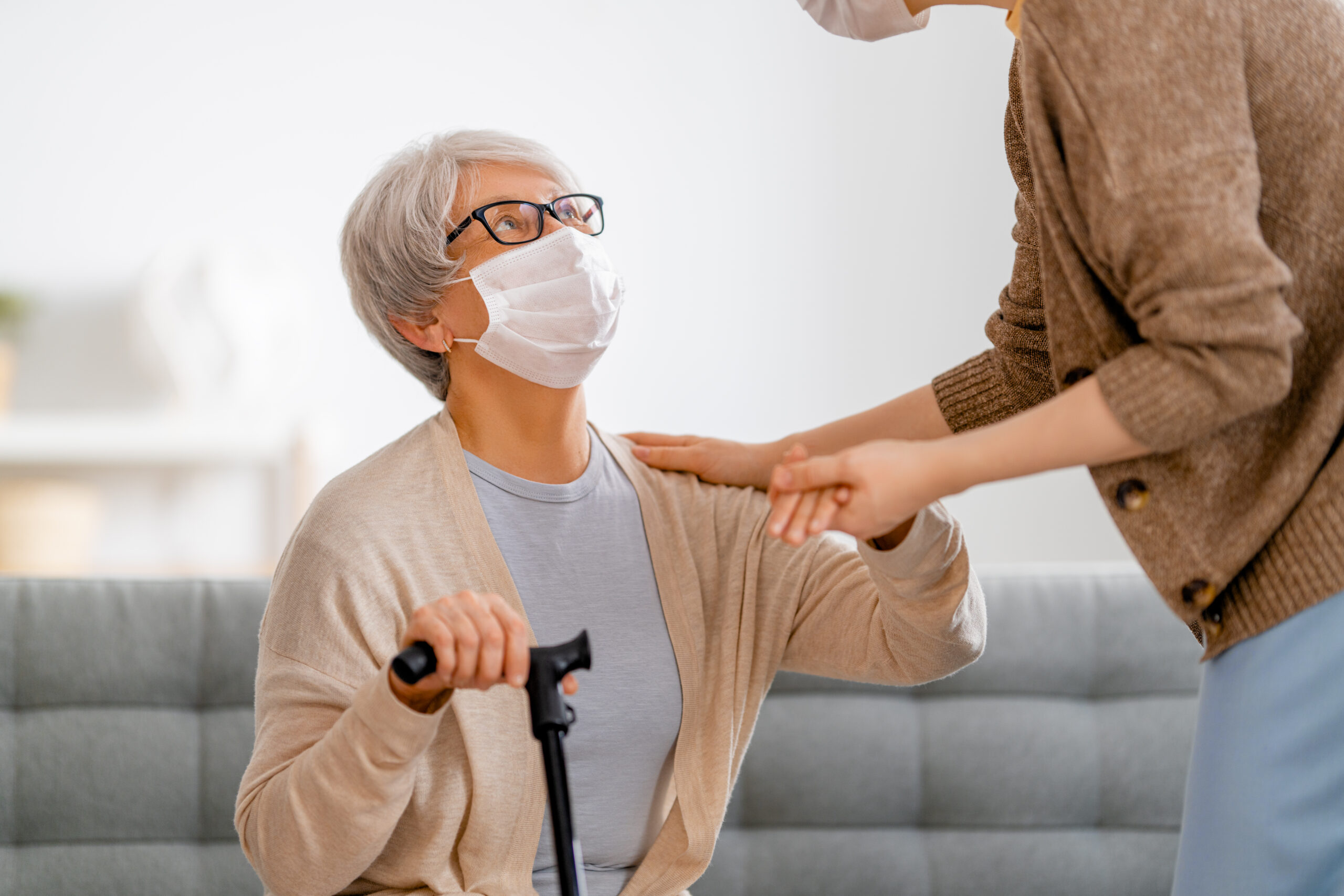Help for the convalescent. Adult daughter and senior parent wearing facemasks during coronavirus and flu outbreak. Help for the convalescent.