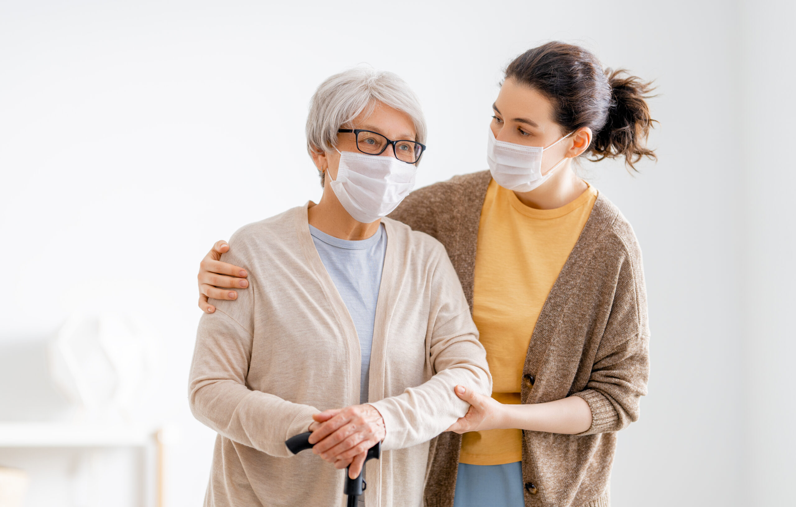 Help for the convalescent. Adult daughter and senior parent wearing facemasks during coronavirus and flu outbreak. Help for the convalescent.