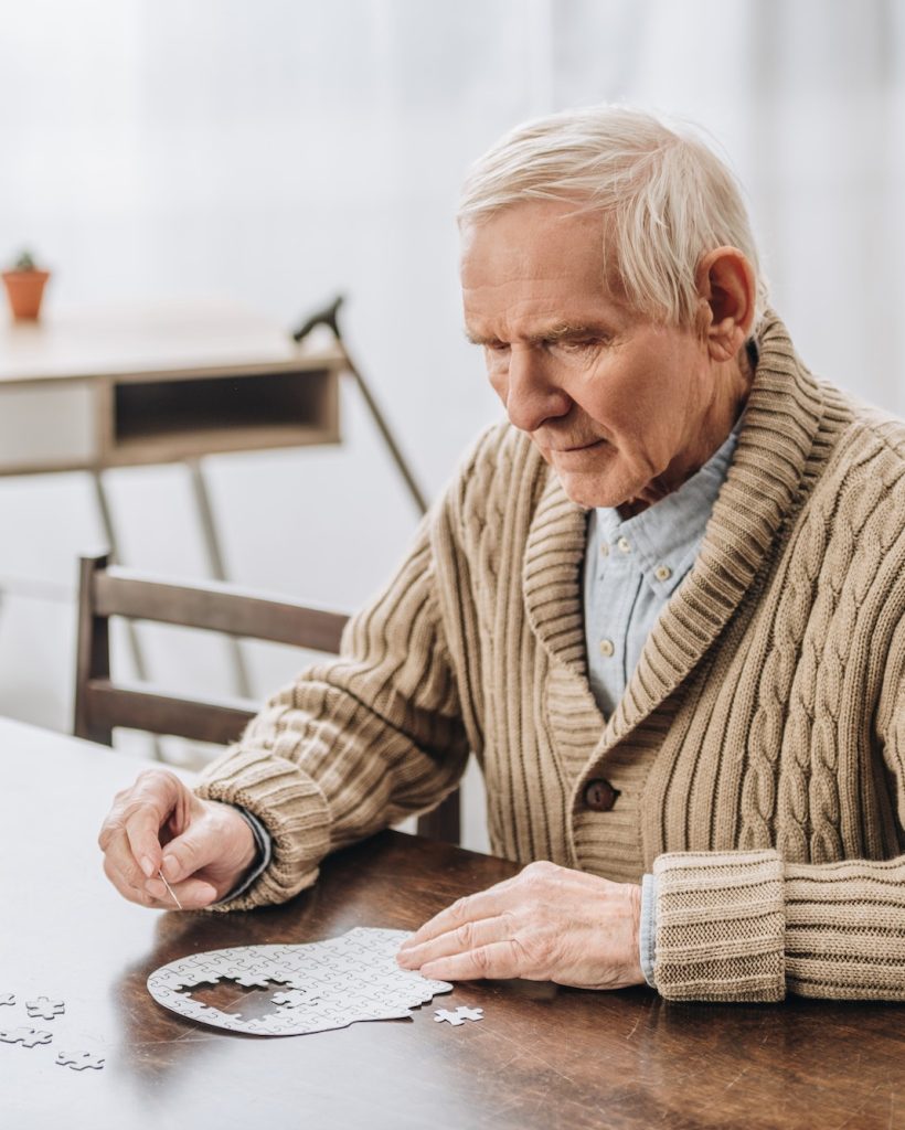 pensioner with grey hair playing with puzzles at home